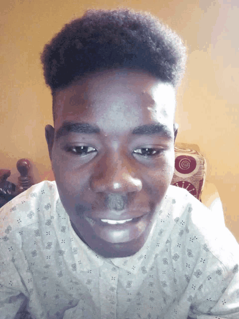a young man wearing a white shirt with a pattern on it smiles for the camera