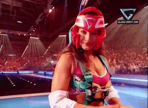 a woman wearing a red helmet is standing on a stage in front of a crowd with a logo for gladiatortv.com