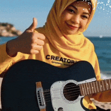 a woman wearing a yellow sweater that says creator giving a thumbs up