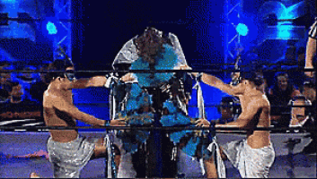 three men are wrestling in a ring and one of them is covered in blue powder