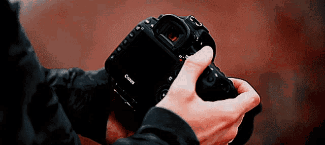 a person holding a canon camera in their hands