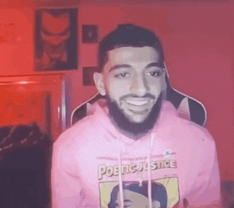 a man with a beard is wearing a pink hoodie .