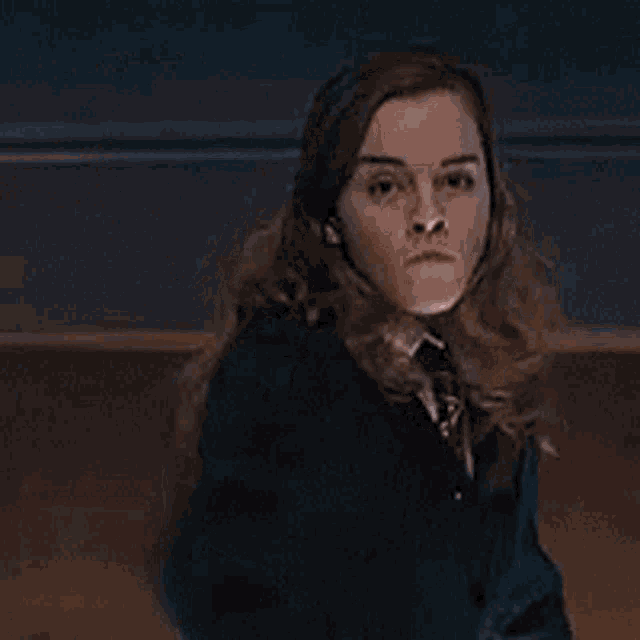 a woman in a school uniform is holding a wand in her hand and pointing at the camera .