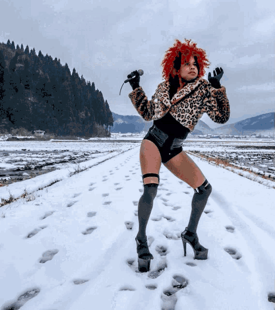 a woman with red hair is standing in the snow with a microphone in her hand