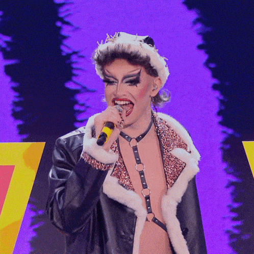 a drag queen is singing into a microphone on stage