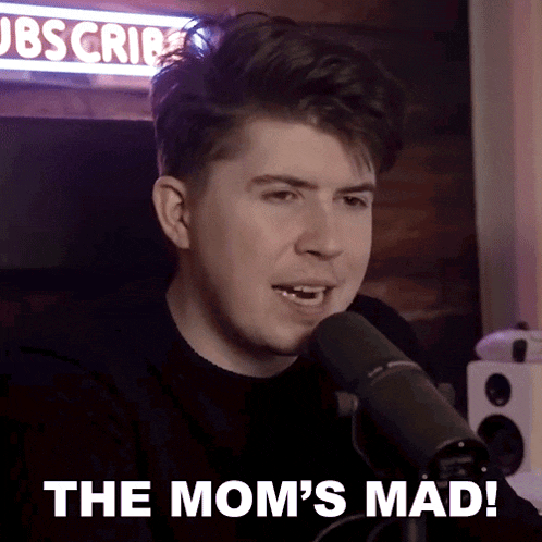 a man sitting in front of a microphone with the words " the mom 's mad " written below him