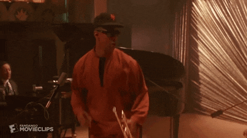 a man in a suit is playing a cello in a band .