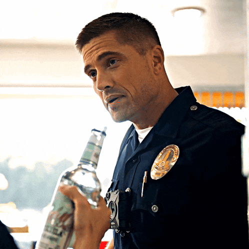 a police officer is holding a bottle of vodka and wearing a badge that says l.a.p.