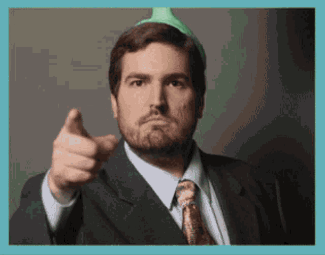 a man in a suit and tie is pointing his finger at the camera