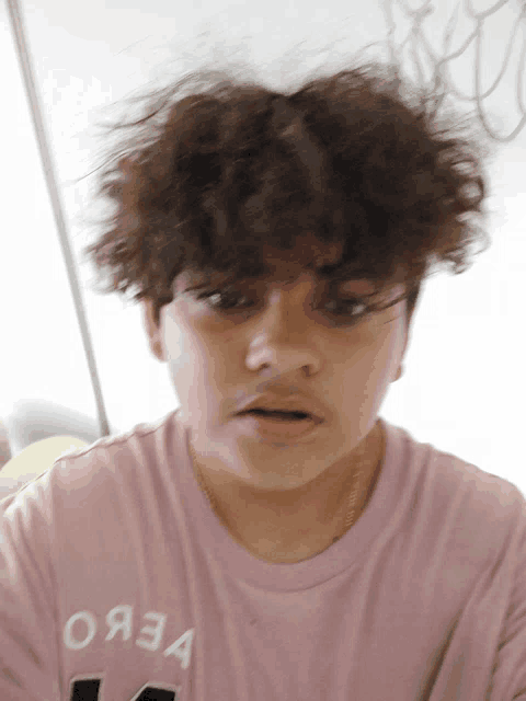 a young man wearing a pink shirt that says oaza on it