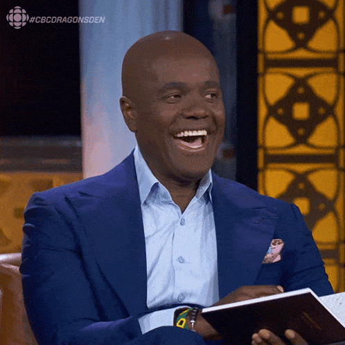 a man in a blue suit is laughing while holding a notebook