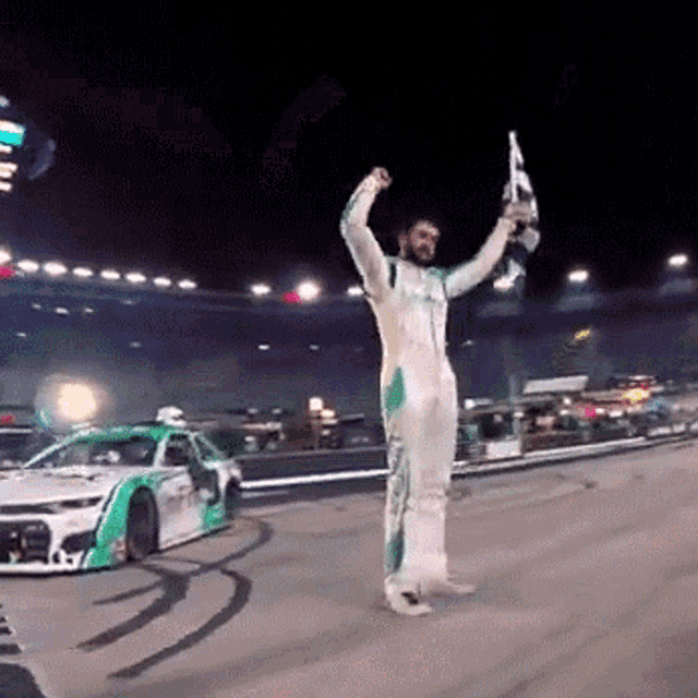 a race car driver is holding a trophy and a flag