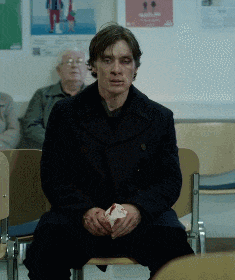 a man in a black coat sits in a chair