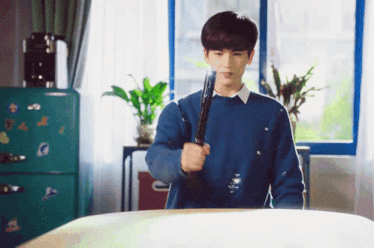a young man in a blue sweater is holding a sword in his hand .
