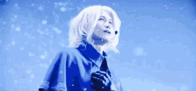 a woman with white hair is standing in front of a blue sky looking up .