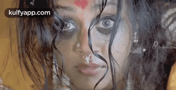 a close up of a woman 's face with a nose ring and a nose piercing .