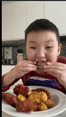 a young boy is eating a plate of chicken wings