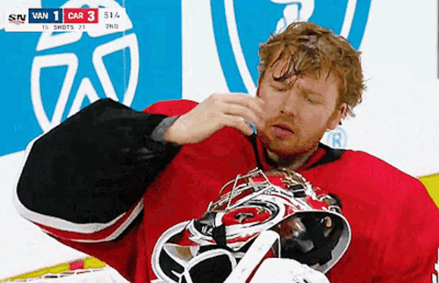 a hockey player wipes his face during a game against van