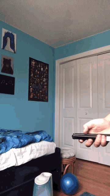 a bedroom with blue walls and a person holding a cell phone