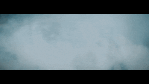 a man is walking through a cloud of smoke in a dark room
