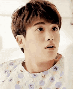 a young man in a hospital gown with hearts on it looks surprised