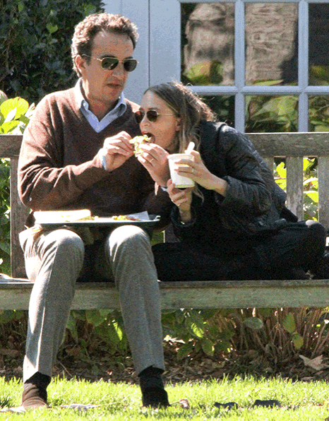 a man and a woman sitting on a bench eating food