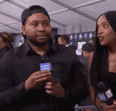 a man is talking to a woman while holding a microphone in his hand .