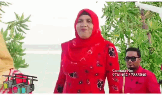 a woman in a red hijab is standing next to a man in sunglasses