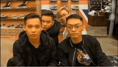 a group of young men are sitting next to each other in a store and one of them is wearing a supreme shirt .