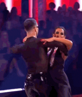 a man and a woman are dancing on a stage with a crowd watching .