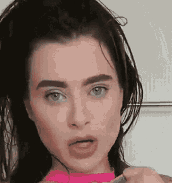 a close up of a woman 's face with a pink choker around her neck