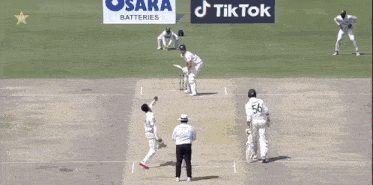 a cricket game is being played on a field with osaka batteries in the background
