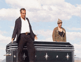 a man standing on top of a black coffin