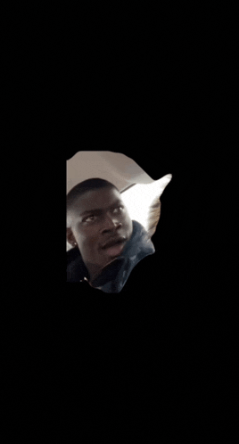a man in a black jacket is looking up in the dark