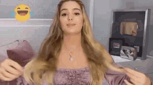 a woman in a purple top is holding her hair in front of a mirror .