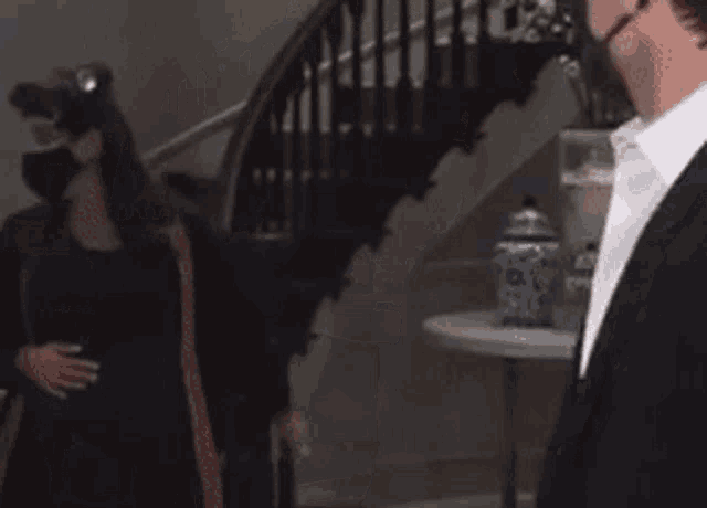 a man in a suit and a woman in a mask are standing next to each other in a room .