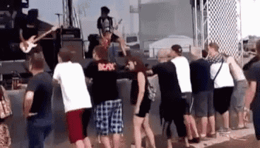 a group of people are standing in front of a stage at a music festival .