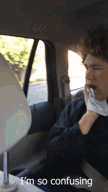 a man sitting in a car with the words i 'm so confusing on the bottom