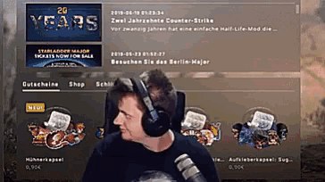 a man wearing headphones sits in front of a 2g years banner