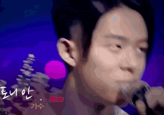 a close up of a man singing into a microphone with chinese writing on the bottom