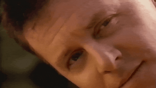 a close up of a man 's face with his eyes closed and a smile on his face .