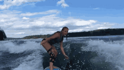 a woman is riding a wave on a surfboard in a lake .