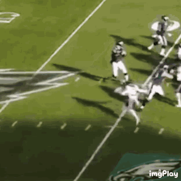 a football game is being played on a field with a eagles logo in the background .