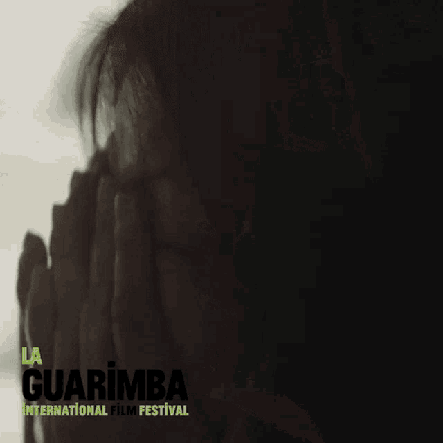 a poster for guarimba international film festival shows a woman covering her face