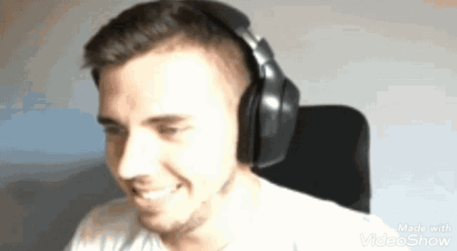 a man wearing headphones is smiling and looking at the camera .