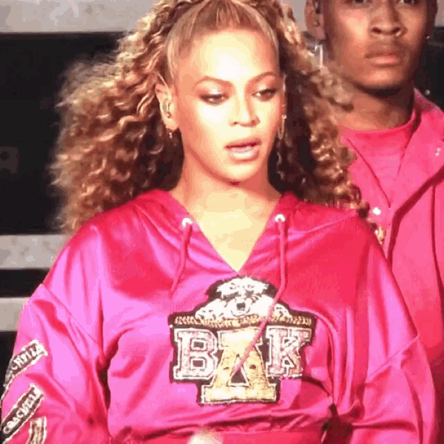 a woman wearing a pink hoodie that says bak