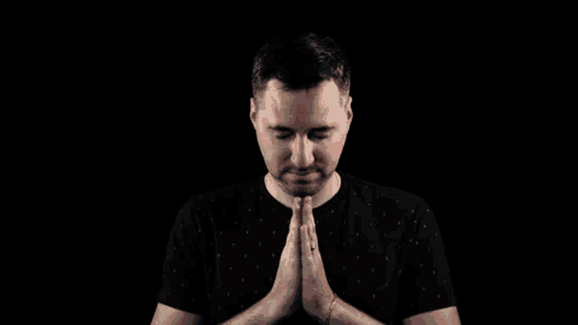 a man is praying with his hands folded in front of his face .