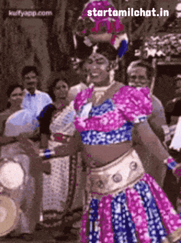 a woman in a pink and blue dress is dancing in front of a crowd with the words starttamilchat.in on the bottom