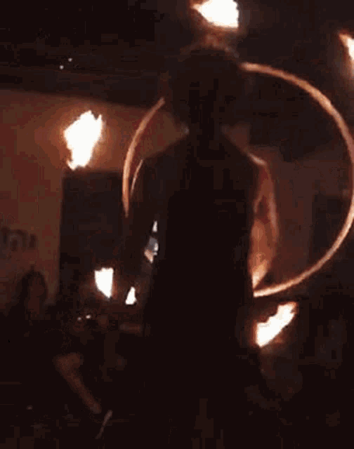 a woman is holding a fire hoop in a dark room while people watch .