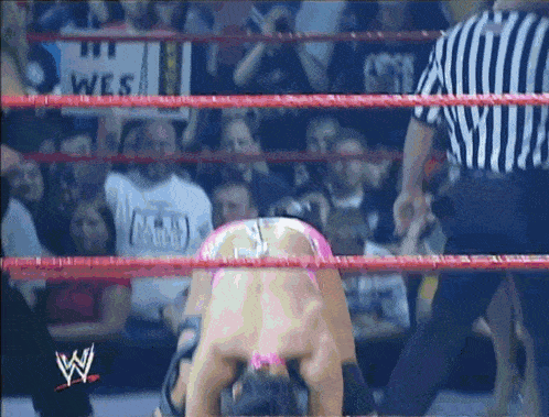 a wrestling ring with a referee and a sign that says wes on it
